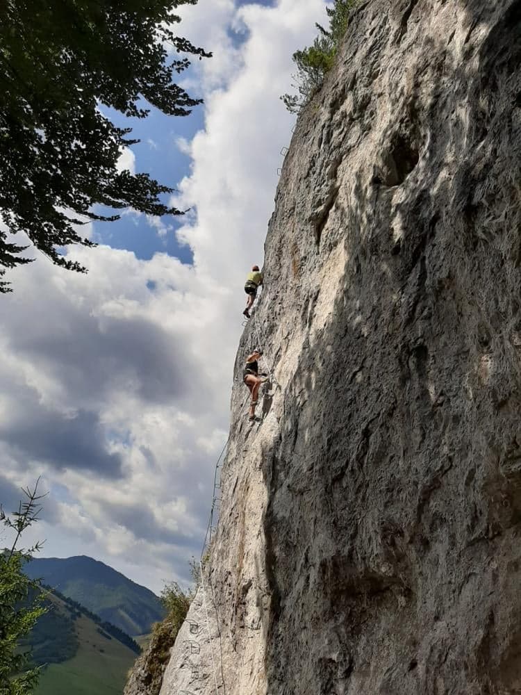 Wspinacz na skalnej ścianie Ferraty Dve veže nad lasem