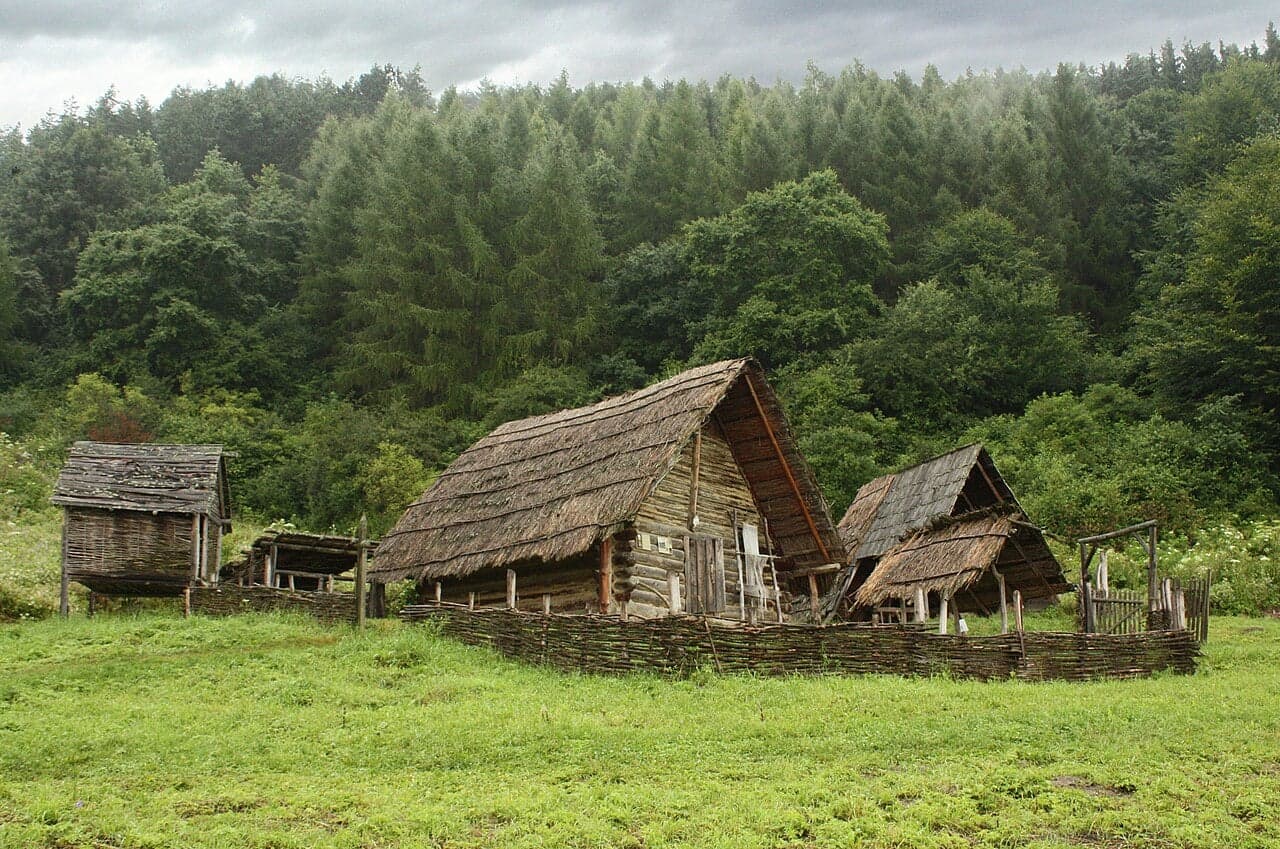 Zrekonstruowane drewniane domostwa w skansenie Havránok na łące pod lasem
