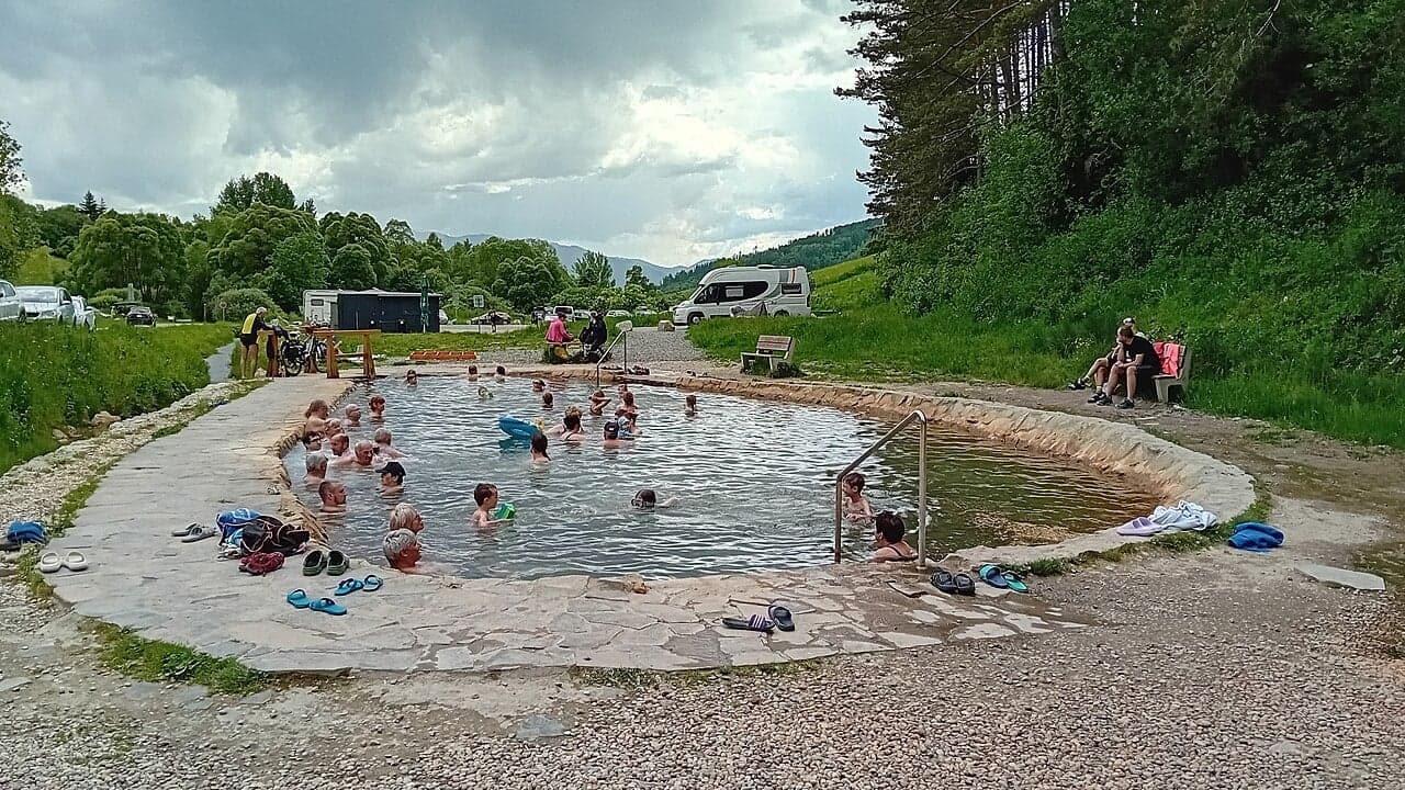 Odwiedzający kąpiący się w zewnętrznym jeziorku termalnym w Kalamenach